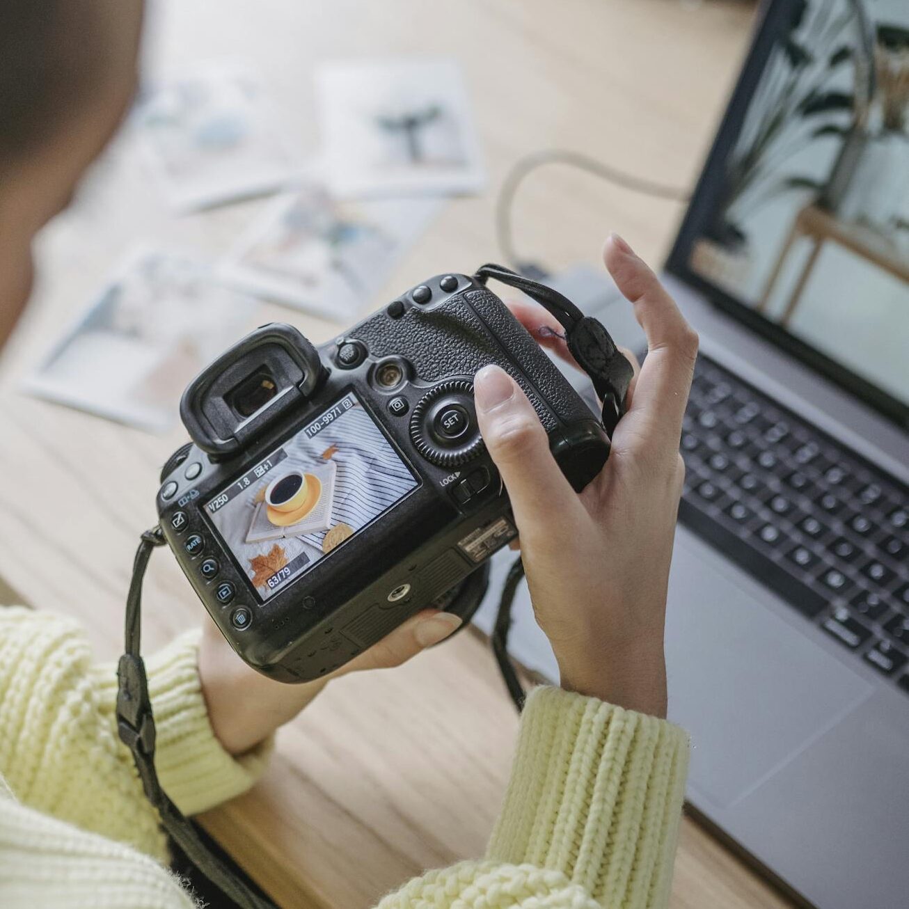 Female photographer reviews and edits images on camera and laptop in studio.